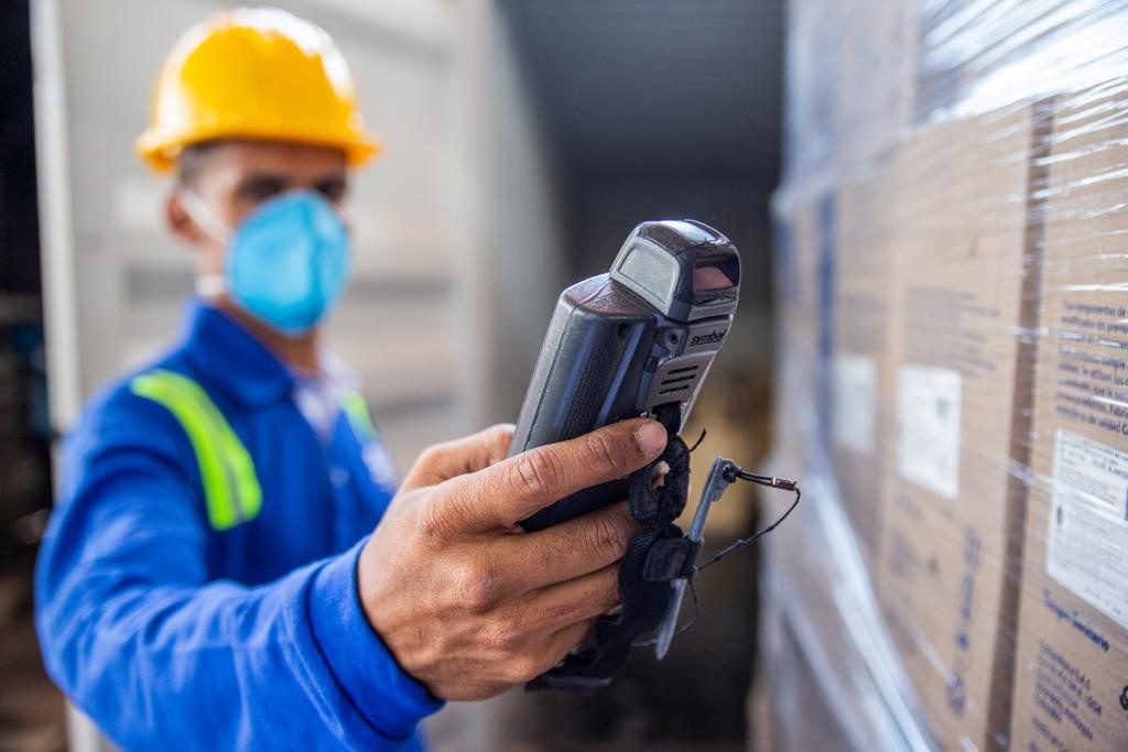 Operario verificando inventario con lector de código de barras en bodega